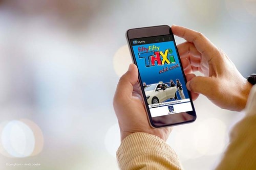 Auf dem Bild sieht man zwei Hände, die die fiftyFifty-Taxi-App auf einem Smartphone bedienen.